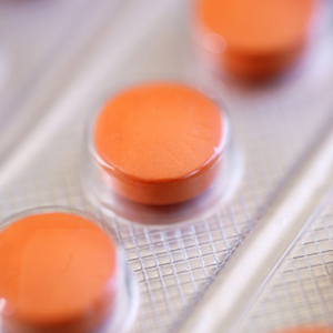 Close-up view of a sheet of orange medicine tablets.