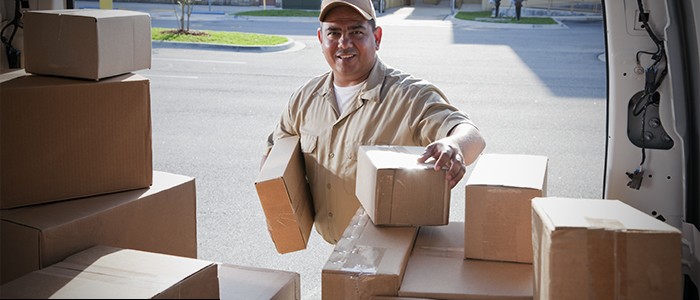Delivery driver removing packages from the back of a vehicle.